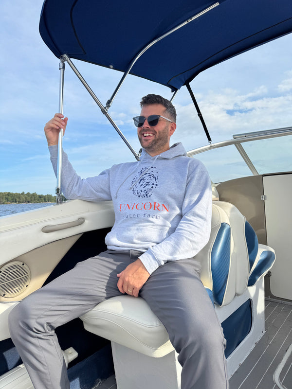 Man in Unicorn Oyster farm sweatshirt on a boat smiling